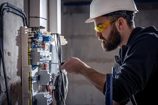 Technician inspecting switchboard and connecting cable.